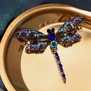 Detailed macro view of a vintage dragonfly brooch with blue and purple crystals