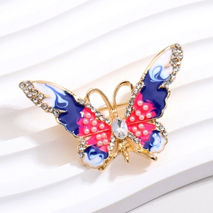 Détail de la broche papillon dorée avec émail bleu et strass scintillants sur les ailes