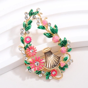 Detailed macro of flower basket brooch with pink enamel, green leaves and crystals