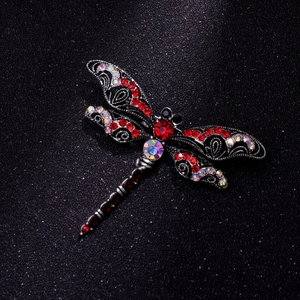 Macro shot of vintage dragonfly brooch with red rhinestones on a black background