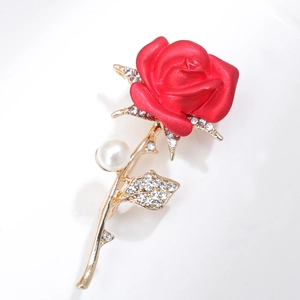 Detailed view of elegant red rose brooch with gold leaves, rhinestones and white pearl