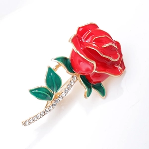 Macro shot of elegant red enamel rose brooch with green leaves and inlaid rhinestones