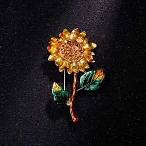 Detailed view of sunflower brooch with golden enamel petals and orange crystal center