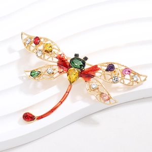 Detail macroweergave van kleurrijke libellenbroche met meerkleurige strass en gouden holle vleugels