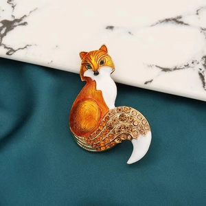 Détail de la broche renard avec émail orange et strass ambrés sur tissu texturé