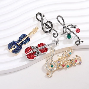 Close-up of music-themed brooches featuring a violin and guitar with colorful rhinestones