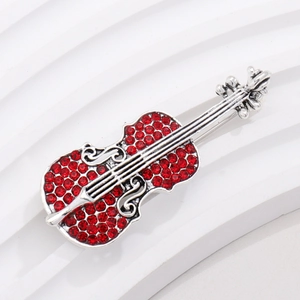 Macro shot of silver-tone violin brooch with sparkling red rhinestones and musical details