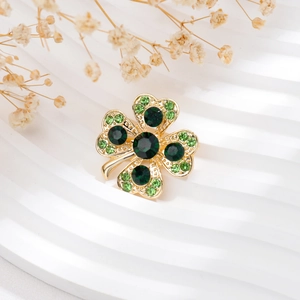 Détail d'une broche trèfle à quatre feuilles avec cristaux verts et finition plaqué or
