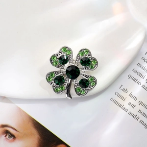 Détail d'une broche trèfle à quatre feuilles avec strass verts sur monture argentée