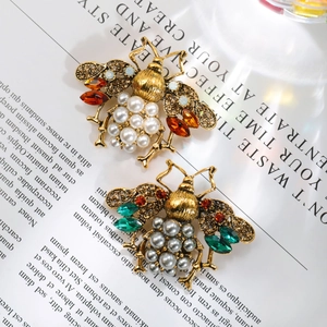 Detail of bee brooch with pearls and crystals on vintage fashion magazine pages