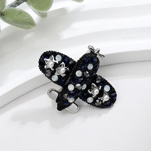 Macro shot of an airplane brooch featuring blue rhinestones and pearls on white decor
