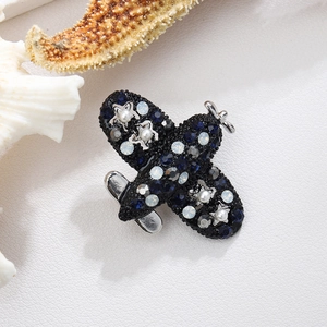 Airplane brooch with blue rhinestones and pearls on a white leather background