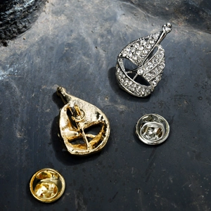 Detailed view of sailboat brooches in gold and silver finish with sparkling rhinestones