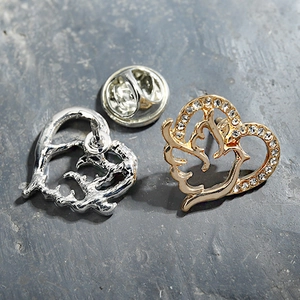 Detail einer herzförmigen Brosche mit Strassrand und Vogelmuster in Gold und Silber