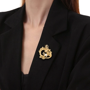 Detail of a vintage golden dragon brooch with a white pearl on a black suit lapel