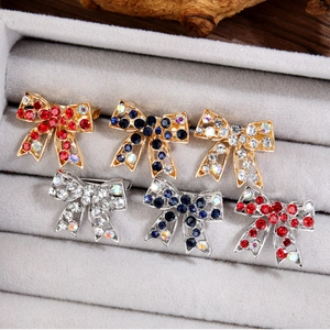 Détail de broches nœud papillon avec strass colorés en finitions or et argent