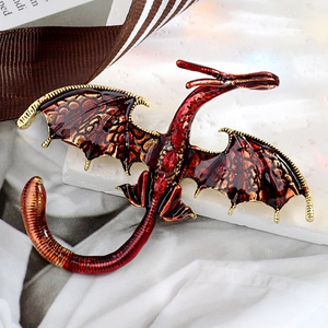 Detail view of red enamel dragon brooch with ruby stones on stone and fabric