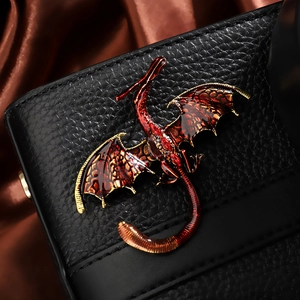Macro shot of vintage dragon brooch with red enamel glaze and gold metal detailing
