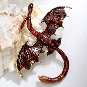Close-up of red enamel dragon brooch with crystal inlay on a decorative shell