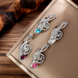 Detailed view of silver music note brooches with colorful teardrop gems and rhinestones