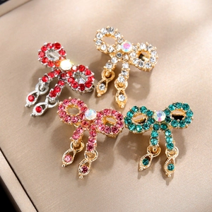 Detailed view of four crystal bow brooches in red, gold, pink, and green colors