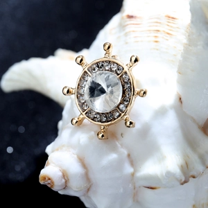 Gros plan d'une broche gouvernail dorée avec cristaux sur un coquillage de conque