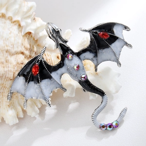 Macro detail of enamel dragon brooch with red marquise rhinestones on a white conch