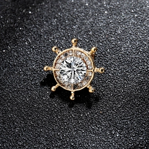 Macro de la broche marin dorée avec pierre centrale et design de gouvernail marin