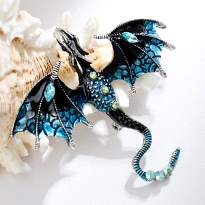 Detailed close-up of a dragon brooch with dark blue enamel wings and sparkling crystals