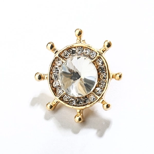 Gros plan de la broche gouvernail dorée ornée d'un cristal central et de petits strass