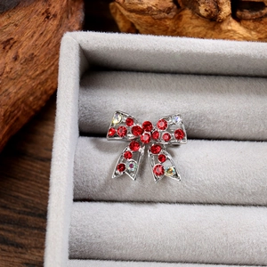 Vue macro d'une broche nœud argentée avec strass rouges et accents de cristaux AB