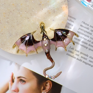 Close-up of vintage dragon brooch with pink enamel wings and sparkling rhinestones