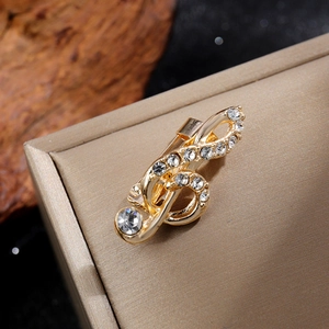 Vue macro d'une broche note de musique dorée ornée de strass sur un écrin à bijoux