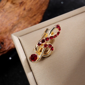 Gros plan sur une broche clé de sol dorée sertie de strass rouges scintillants