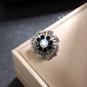 Detalle macro de broche de flor plateada con pétalos azul oscuro y piedra brillante