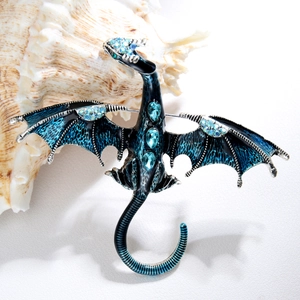 Close-up of blue enamel dragon brooch with inlaid rhinestones on a white conch shell