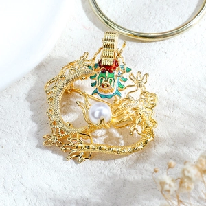 Detail of vintage dragon brooch with green enamel accents and a lustrous white pearl