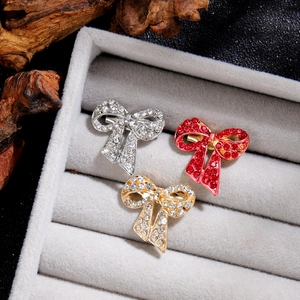 Vintage-Schleifenbroschen in Gold, Silber und Rot mit Pavé-Kristallen auf Schmucktablett