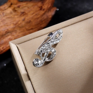 Vue macro d'une broche en forme de note musicale argentée avec strass sur soie