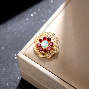 Detalle de broche de girasol dorado con cristales rojos y centro de estrás AB