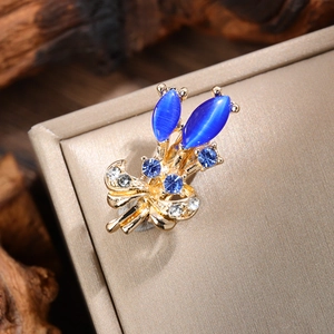 Macro shot of tulip brooch with blue cat-eye stones and diamonds on silk jewelry box