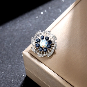 Detalle del broche de flor con cristales azules y piedra central blanca irisada