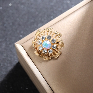 Macro de un broche de flor dorada con piedra central irisada y diamantes imitación