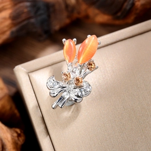 Macro shot of silver bouquet brooch with orange opals and crystal bow detailing