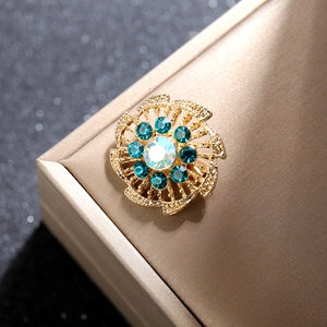 Vista macro del broche de flor dorada vintage con diamantes azules y piedra central irisada