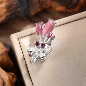 Macro shot of silver tulip brooch with pink cat eye stones and purple crystals