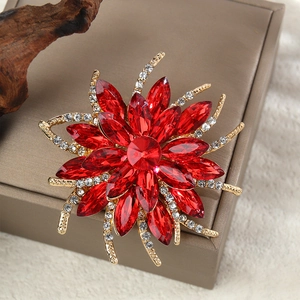 Détail d'une broche fleurie en pierres rouges marquises et cristaux sur boîte en cuir