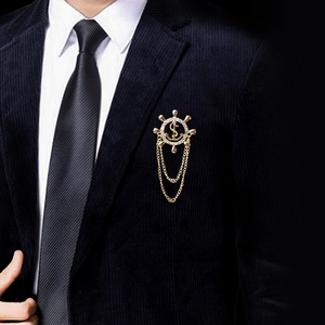 Golden ship wheel and anchor brooch with crystal dollar sign on a navy suit lapel