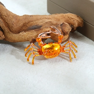 Detailansicht der Krabbenbrosche mit orange-gelber Emaille auf Naturholzdekor