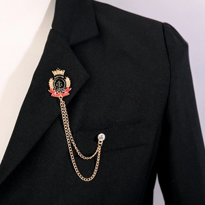 Vintage gold brooch with crown crest, anchor emblem and chain on a black blazer lapel